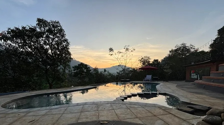 Pool at sunset with golden sky reflecting on the water at Holistic Eco-Resort