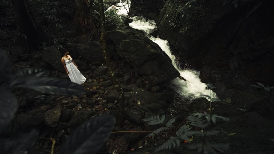 Lady in white dress by the forest waterfall